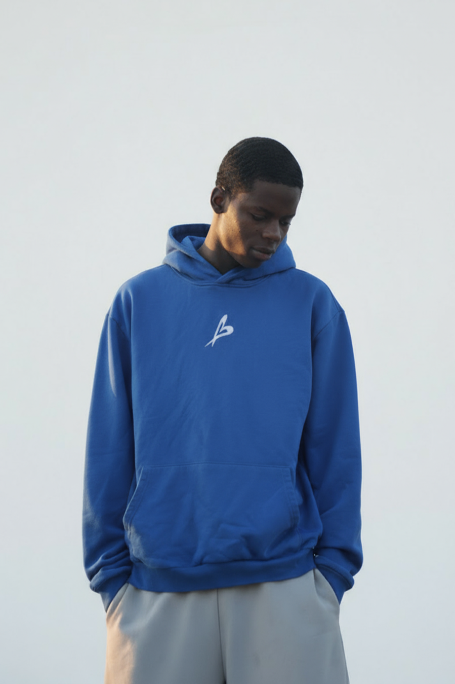 Person wearing a blue hoodie with a logo on a plain background
