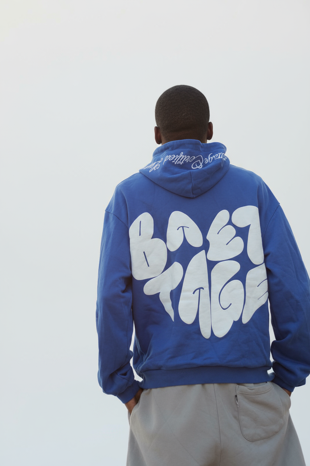 Person wearing a blue hoodie with white text on the back against a light gray background